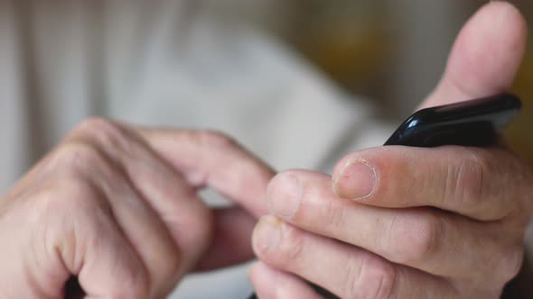 Pensioner with a phone is typing a message