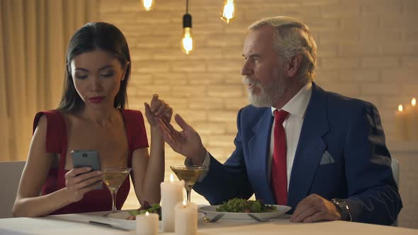 Young Lady Using Smartphone on Date, Ignoring Old Man Flirting, Relationship