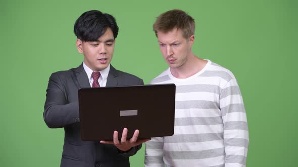 Young Handsome Asian Businessman and Young Scandinavian Businessman Working Together