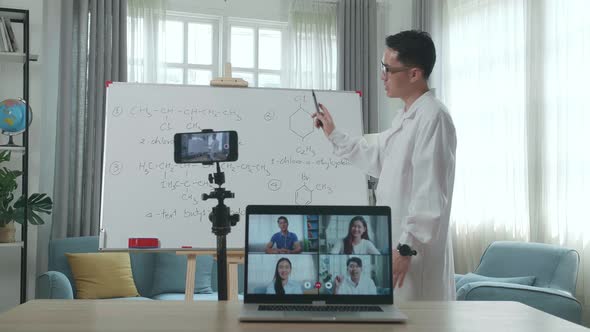 Asian Male Teacher Teaching Chemist Online At Home With Students In Laptop Screen