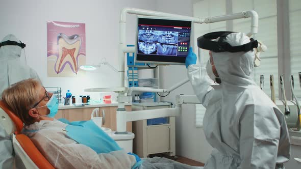 Doctor with Face Shield Pointing on Stomatological Monitor