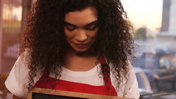 Smiling waitress showing slate with open sign