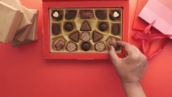 Reaching Dark Chocolate in a Bow on Red Background