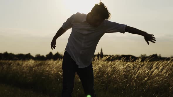 Slow motion shot of young man dancing outdoors against sun