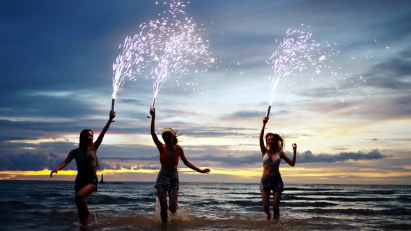 4K Group of Young Asian woman playing sparkler fireworks together on the beach at summer sunset.