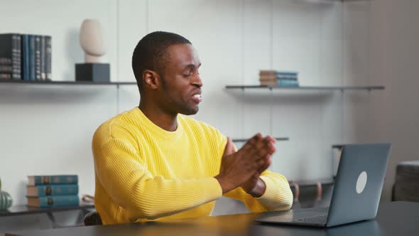 Young man having video conference using laptop at the desk at home