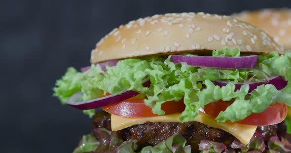 Freshly Cooked Burger with Lots of Vegetables and a Large Beef Patty on a Gray Background.