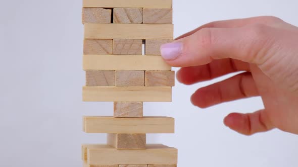 Female Hand Playing Wooden Block Removal Tower Game at Home