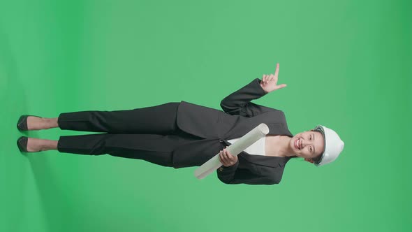 Full Body Of Female Engineer Holding Blueprint And Pointing To The Side In The Green Screen Studio