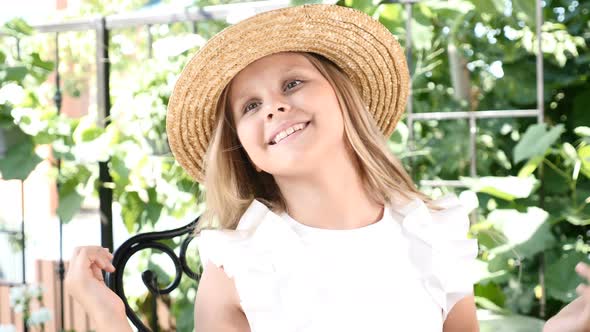 Cuty Little Girl in a Straw Hat Laughing and Smiling at Camera