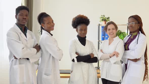 A Team of Doctors Including Men and Women From Different Countries Look at the Camera While Standing