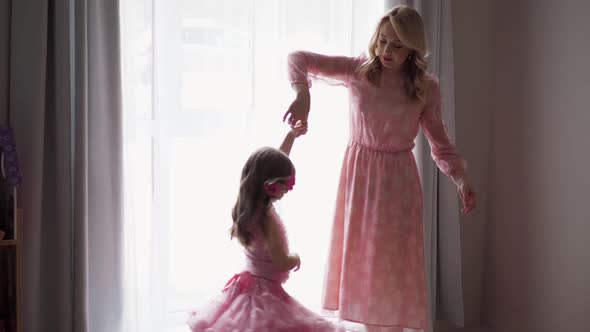 Backstage the Photographer with Beautiful Family Mother and Daughter in Pink Dress Near Large Window