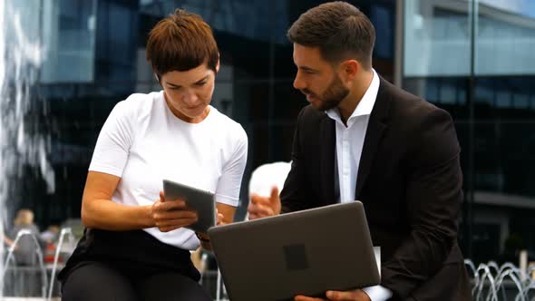 Businesspeople discussing on digital tablet and laptop