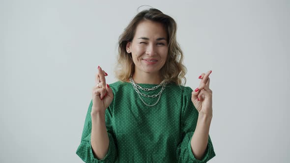 Portrait of Happy Girl Crossing Fingers and Smiling Making Wish on White Background