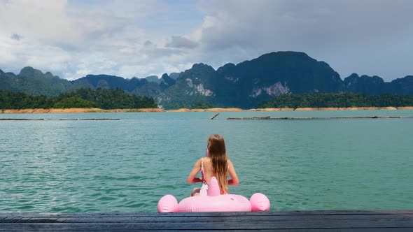 Happy Woman Have Fun and Fool Around at Pink Inflatable Flamingo on Blue Lake