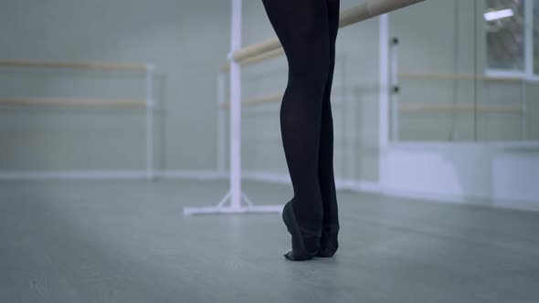 Slim Female Legs in Pointes in Ballet Studio As Graceful Ballerina Sitting Down on Floor Bending