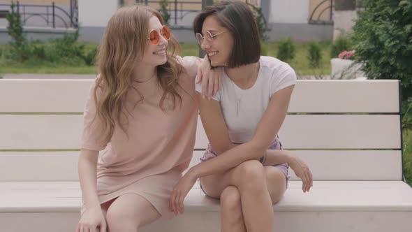 Sexy carefree women sitting on the bench on street background