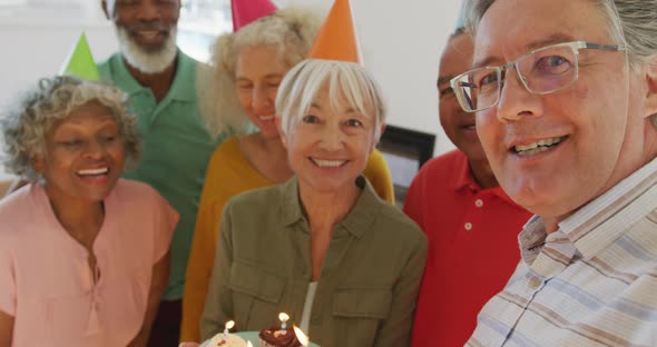 Portrait of happy senior diverse people at birthday party with cake at retirement home