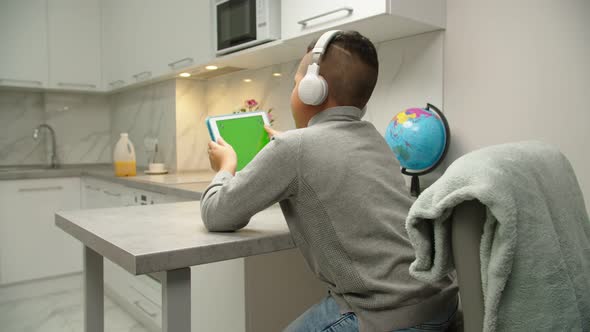 Cute Black Kid in Headphones Using Tablet Gaming at Home