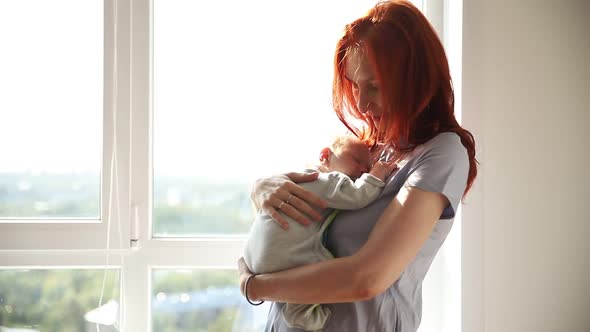 Ginger Woman Mother Holding Her Baby and Pats His Back