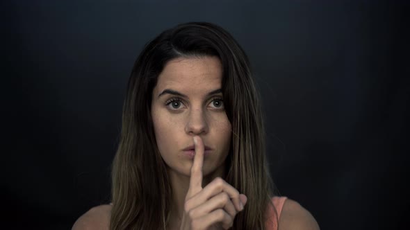 Woman holding finger to lips in silence
