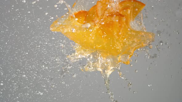 Orange juice with sliced oranges exploded and splashed in the air. Slow Motion.