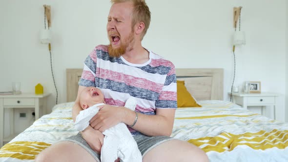 tired father with baby in their arms shouting while sitting on the bed