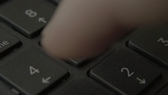 The Finger Presses a Button with a Number on the Keyboard