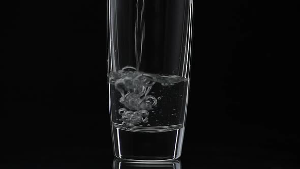 Pouring Up Shot of Vodka Into Drinking Glass. Slow Motion. Black Background