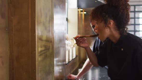 Mixed race female chef preparing a dish and smiling in a kitchen