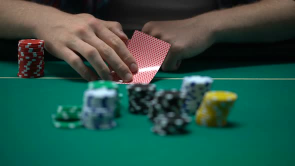 Man Checking Cards and Raising, Bluffing During Poker Tournament, Chance to Win