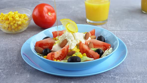 Chef Pour with Oil Colorful Fresh Vegetable Salad with Mozzarella Cheese in Blue Bowl Closeup