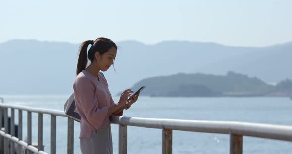Woman use of mobile phone with sea background