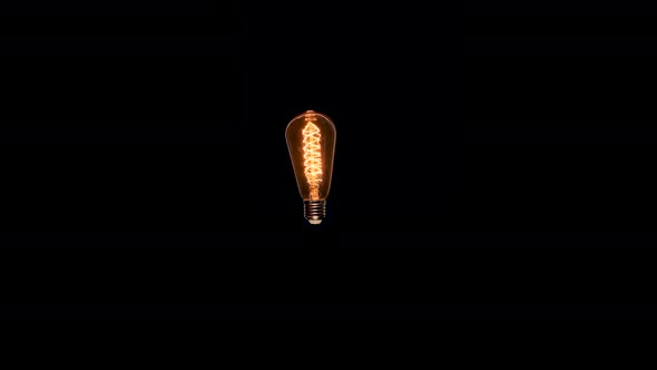 Edison Dirty Lamp with Dust Inside Glass, Flicker on Black Background. Amber Tungsten Color Old