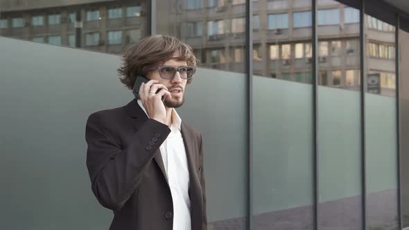 Businessman talking to employees on the phone near the office