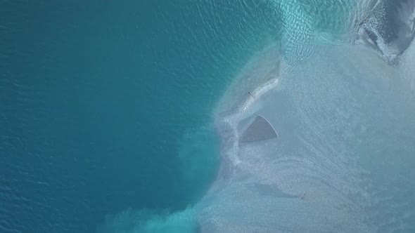 Drone flying above partially frozen lake surface. Top down view to the icy water