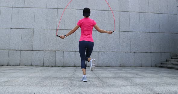 Fitness woman jumping rope in city