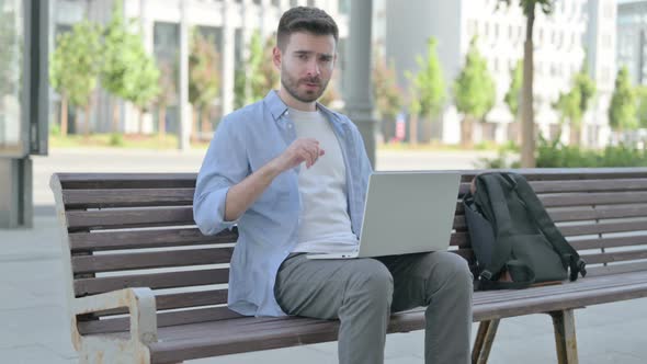 Thumbs Down By Young Man with Laptop Sitting on Bench