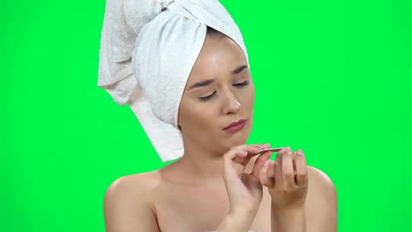 Woman with a Nail File Takes Care of Nails. Girl with a Towel on Her Head on Green Screen. Close Up