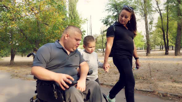 Wheelchair Man. Handicapped Man. Young Disabled Man in an Automated Wheelchair Walks with His Family