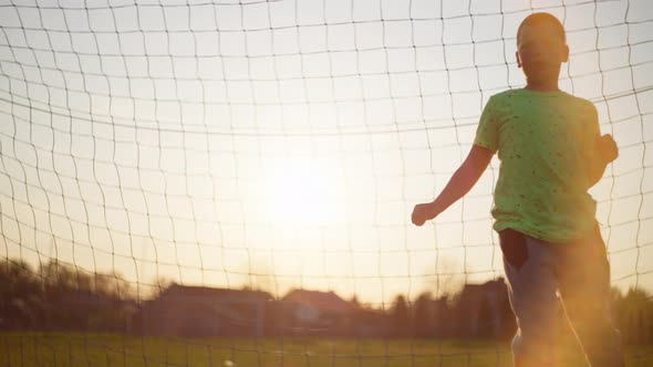 The Boy Catches the Ball in the Football Goal