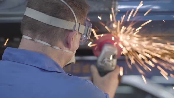 Back View Close-up of Male Caucasian Worker Using Metal Grinder. Professional Man Working in Auto