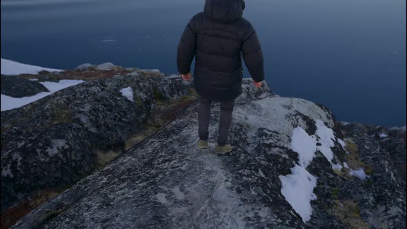 Man Walking Over Coastline Rocks Towards Calm Sea