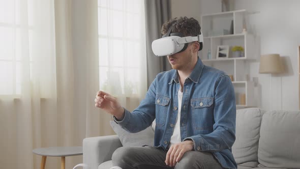 Young Caucasian Man Wearing Virtual Reality Glasses at Home in the Living Room