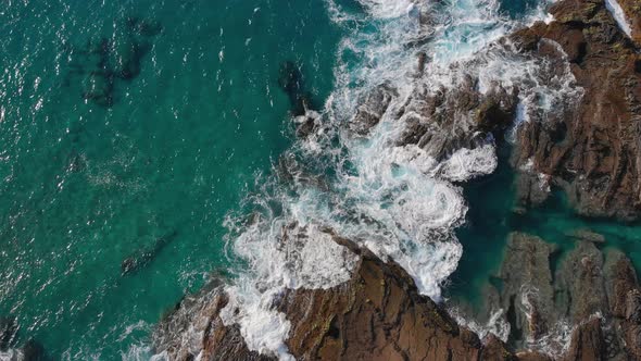 Top down view of the waves crashing against the rocky shore at Porto das Salemas