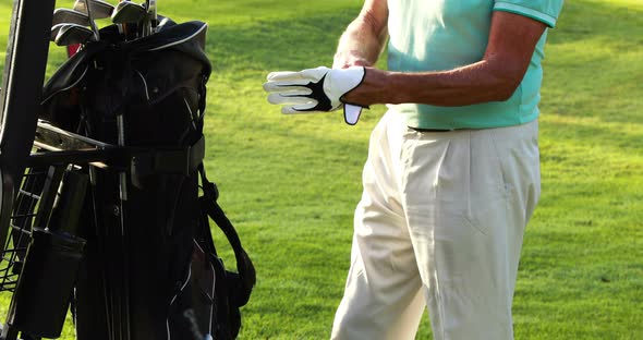 Mid section of male golfer wearing golf glove