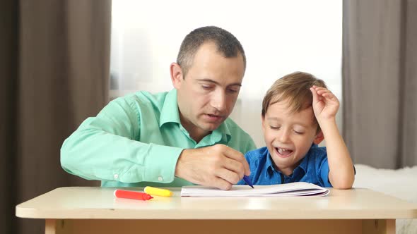 A Mature Father Spends Time with His Young Son, Drawing with Colored Pencils.