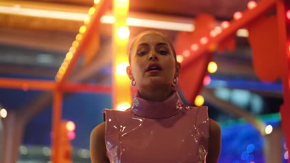Woman In Pvc Clubwear Posing To Camera Amongst Neon Lights