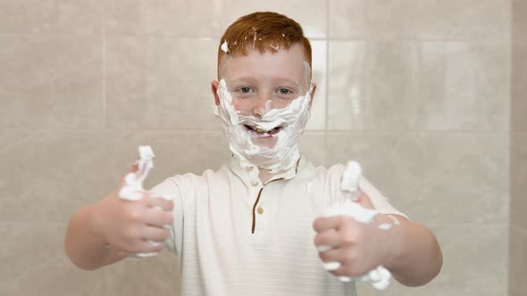 Funny Boy in the Bath with Shaving Cream on His Face Shows a Sign of Consent with His Thumb Up