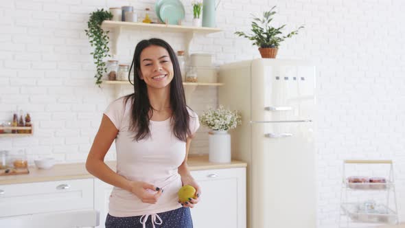 Happy Young Beautiful Woman with Green Apple Standing in the Kitchen